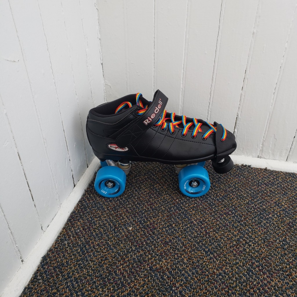 A flat heel quad skate with blue wheels and rainbow laces.